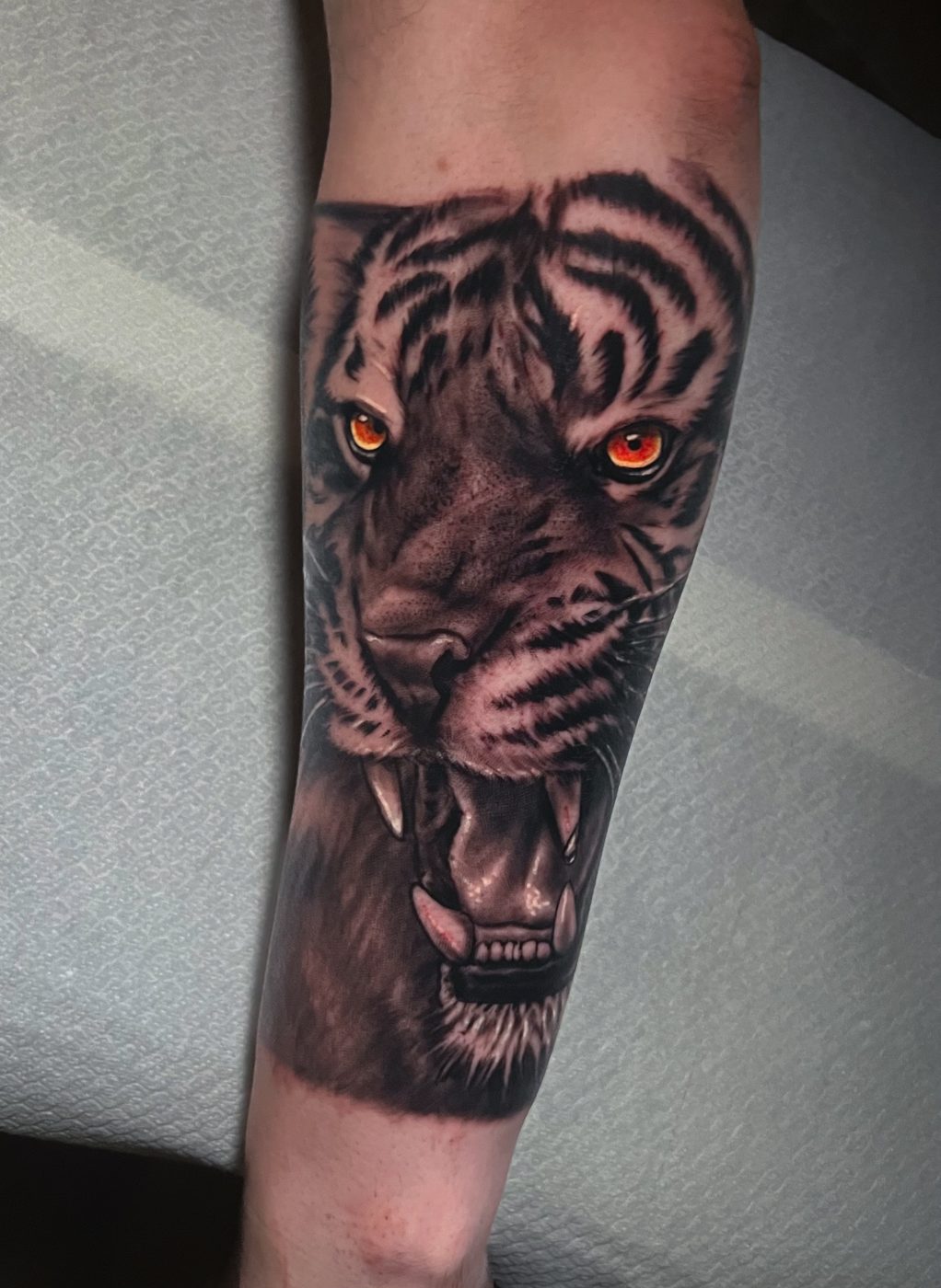 Tigre realista con ojos naranjas en el antebrazo